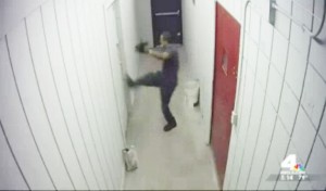 Terlihat seorang pencuri toko sedang berusaha melarikan diri dengan cara menjebol pintu.